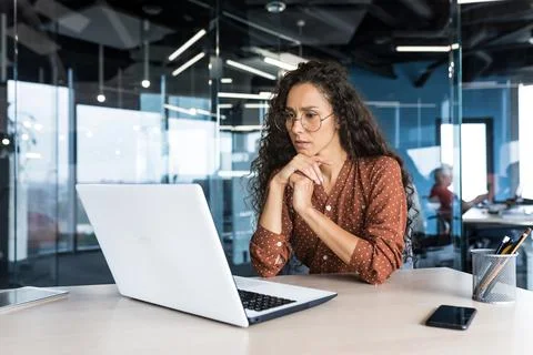 Pensive and focused female programmer web developer working in modern product Stock Photos