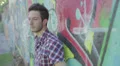 pensive and sad man is crying leaning against a wall painted with murals HD Footage