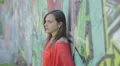 pensive and sad woman is crying leaning against a wall painted with murals HD Footage