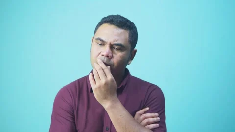 Pensive Asian Man Thinking With Hand on Chin in Blue Studio Background Stock Footage 331952638
