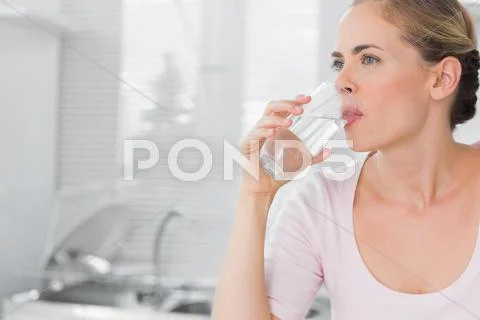 Pensive blond woman drinking water Stock Photos
