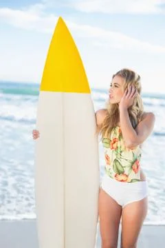 Pensive blonde model in swimsuit holding a surfboard Stock Photos