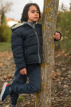 Pensive boy leaning on tree trunk in nature Stock Photos