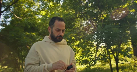Pensive brunette man with a beard puts on wireless headphones and listens to Stock Footage 280622551