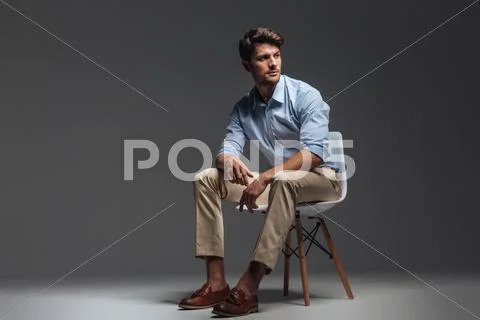 Pensive brunette man in blue shirt sitting on the chair Stock Photos