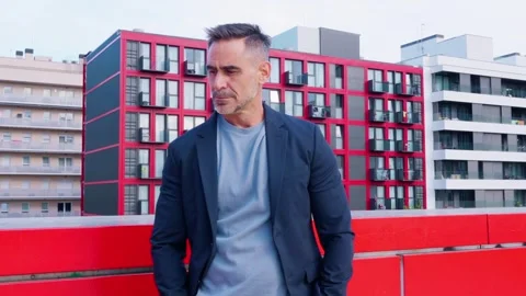 Pensive businessman looking down on rooftop with urban cityscape Stock Footage 295408256