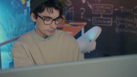 Pensive businessman reading documents and looking at computer monitor in dark Stock Footage 166818557