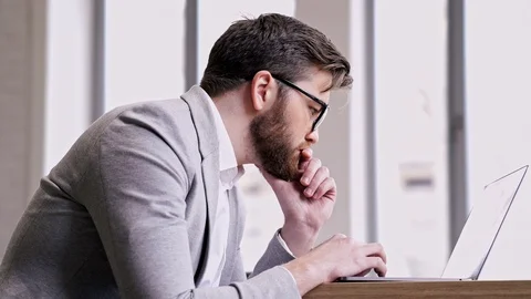 Pensive businessman using laptop computer and thinking in office Stock Footage 87786234