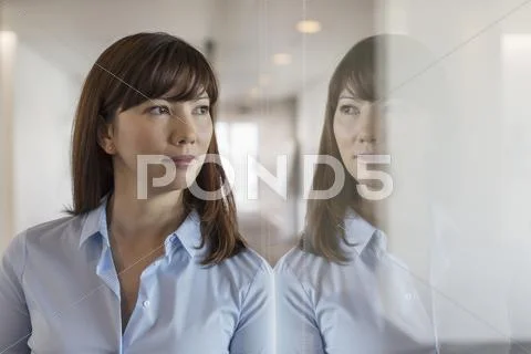 Pensive businesswoman looking out office window Stock Photos