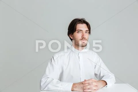 Pensive calm man in white shirt sitting at the table Stock Photos