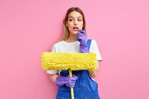 Pensive caucasian woman with mop in hands going to clean, wash the floor Stock Photos