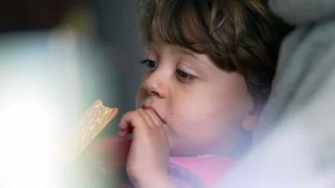 Pensive child eating cookie while laid down on couch, close-up face of smal.. Stock Photos