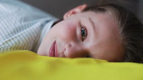 A Pensive Child Lying on a Soft, Cozy Yellow Blanket in a Calm and Comfortable Stock Footage 318708396