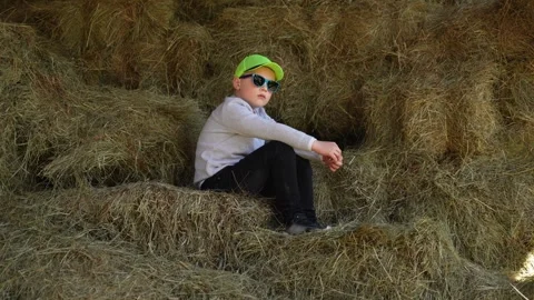 A pensive child sits in a haystack Stock Footage 242746165