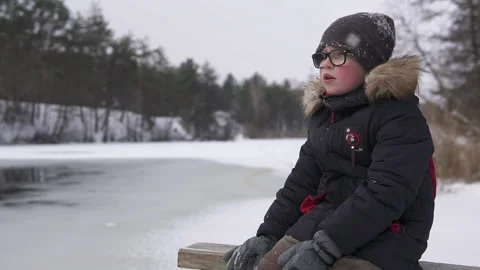 A pensive child sits by the river in the winter season. Hanging out in quarantin Stock Footage 166207149