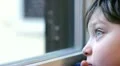 pensive child steams up the glass of the window with the breath HD Footage