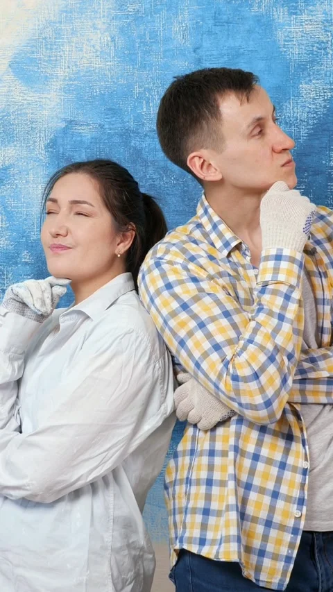 Pensive couple standing back to back contemplating a home improvement project 库存影片 342906241