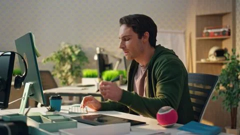 Pensive creator watching computer screen at office. Freelance man using tablet Stock Photos