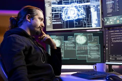 Pensive cybercriminal coding on PC, brainstorming ways to evade security Stock Photos