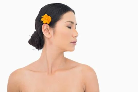 Pensive dark haired model with orange flower in hair Stock Photos