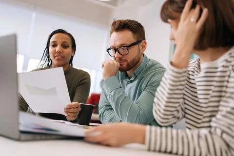 Pensive diverse group creative designers cooperating at office conference room Stock Photos
