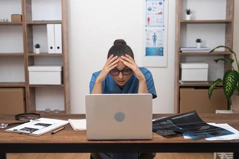 Pensive doctor solves complex issues regarding patient treatment resting head on Foto stock