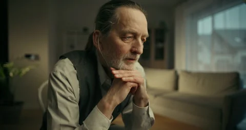 Pensive elderly man sitting alone in a warm living room Vídeo Stock 336280059