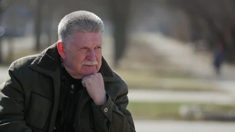 Pensive elderly man sitting outdoors and thinking about something Stock Footage 104256394
