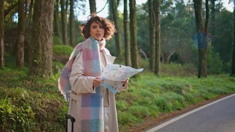 Pensive explorer looking map in forest road at autumn vacation. Woman traveler Stock Photos