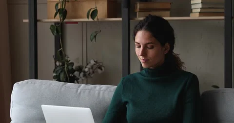 Pensive female sitting on sofa thinking working on laptop Stock Footage 146295441