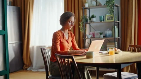 Pensive freelancer working project sitting apartment kitchen. Woman typing home Stock Footage 333381435