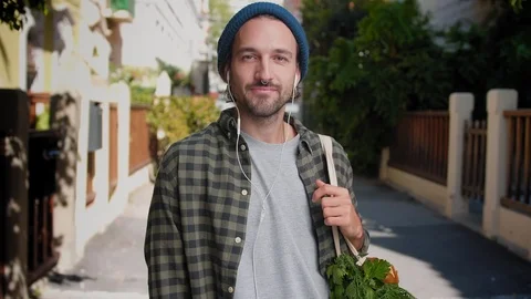Pensive guy in blue hat listening song using white headphones and holding Stock Footage 111071528
