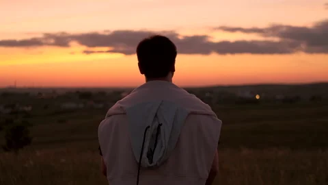A pensive guy raises his hands up and admires the sunset. Stockbeeldmateriaal 162263615
