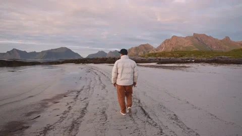 A pensive guy walks against the backdrop of the Lofoten mountains at sunset Stock Footage 219344802