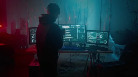 Pensive hacker walking near three display with information Stock Footage 257384702