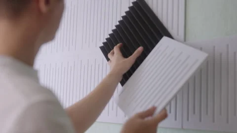Pensive handyman choosing between two types of soundproof wall panels, comparing Stock Footage 325713727