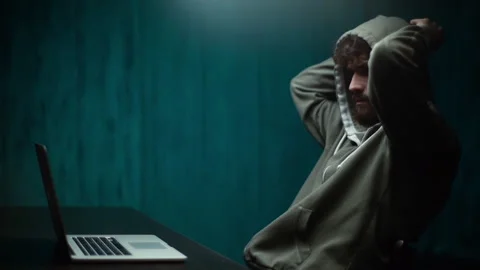 Pensive hooded male hacker programming on laptop and breaking password, side Stock Footage 142510652