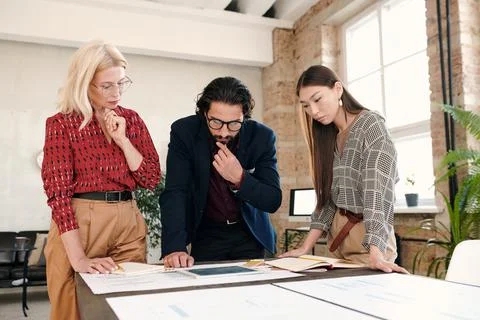 Pensive intercultural mobile application developers looking at tablet display Stock Photos