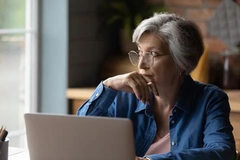 Pensive lady retiree study computer ponder on next step 스톡 사진