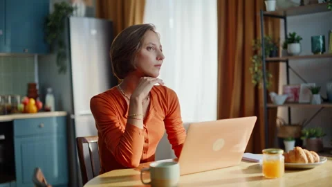 Pensive lady typing laptop sitting apartment kitchen closeup. Woman thinking Stock Footage 333341384
