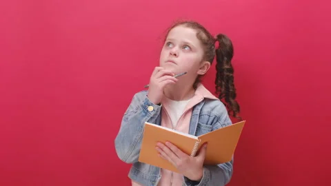 Pensive little girl making notes, writing down thoughts with pen into notepad Stock Footage 239719869