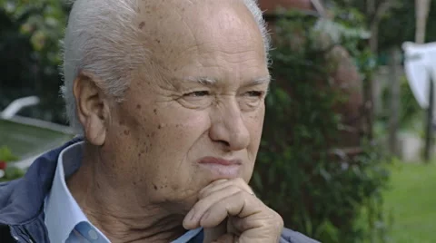 Pensive lonely old man sitting in the garden: closeup portrait looking in camera Video stock 68762216
