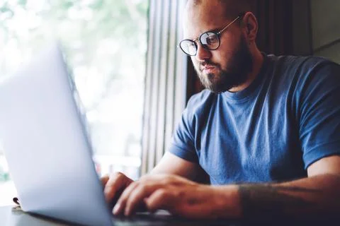 Pensive man browsing laptop working in modern workspace Stock Photos
