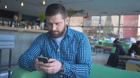 Pensive man browsing smartphone, smiling at camera, cafe portrait steadicam shot Vidéo 72946905