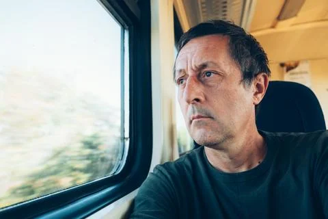 Pensive man commuting by train looking out the window as scenery blurs past.. Fotos Stock