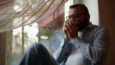 Pensive man drinking coffee and enjoying view from the window Stock Footage 71658048
