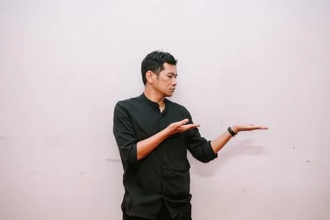 Pensive man presenting or displaying product on empty space Stock Photos