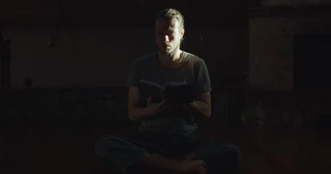 Pensive man reading paper book indoors enlightened by sun rays. Concentrated Stock Footage 150642317