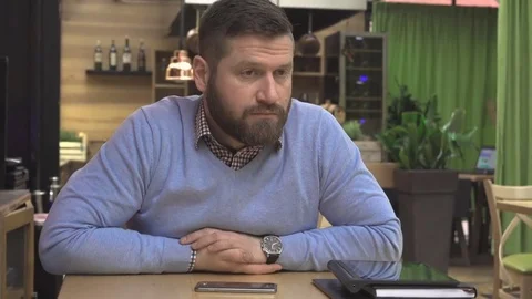 Pensive man, sitting at table, in pub, cafe, indoor, steadicam shot 库存影片 73069015