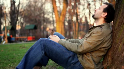 Pensive man sitting by the tree, dolly shot Stock Footage 943230